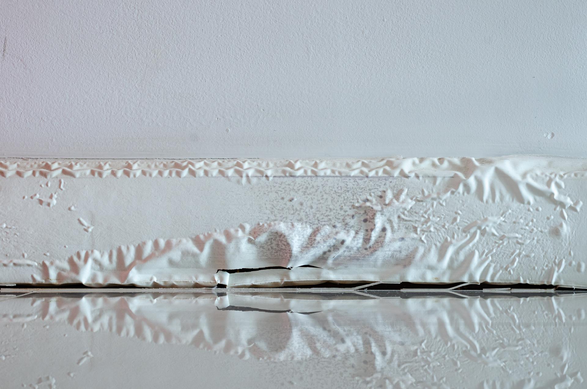 White skirting board damaged by destructive elements from moisture or water.